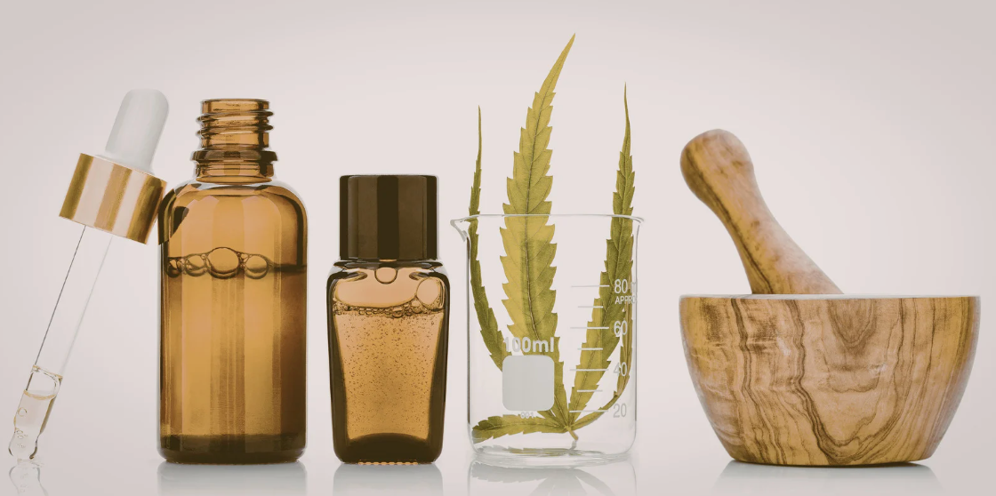 琥珀色精油瓶、滴管小瓶、玻璃燒杯中的綠色葉片與木製研缽，呈現天然植物護膚與成分調配意象